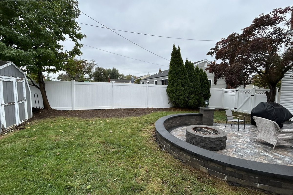 Clean stone patio and white vinyl fence after professional exterior cleaning services in Long Island.